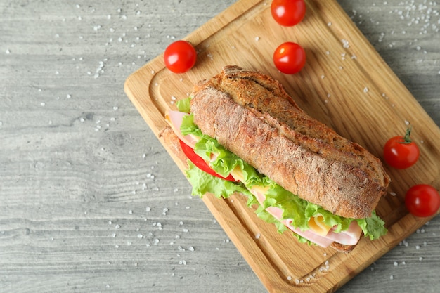 Tabuleiro com sanduíche de ciabatta em mesa texturizada cinza