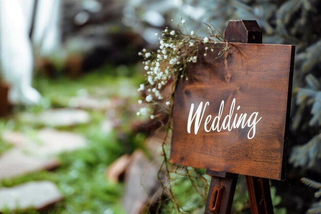 Foto tabuleiro de madeira com a inscrição em pintura sinal de casamento para convidados na entrada ao ar livre decoração da cerimônia de casamento tabela de sinalização de boas-vindas de casamento placa de madeira com jardim em fundo