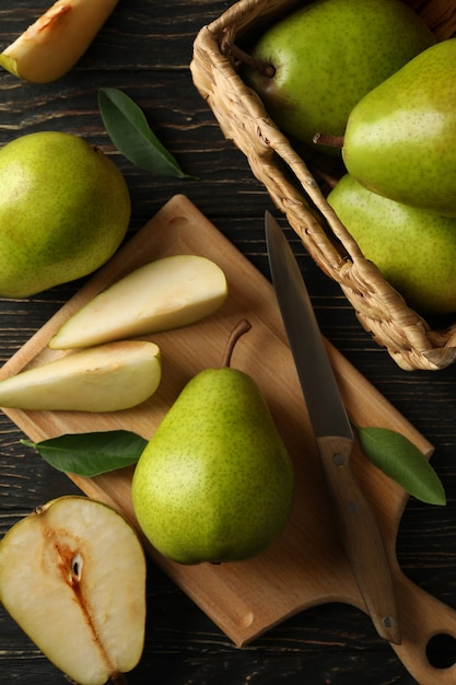 Tabuleiro e cesto com peras verdes na mesa de madeira