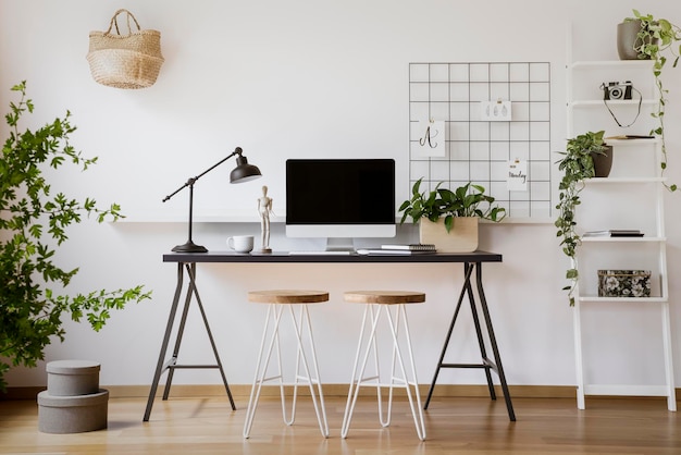 Foto taburetes en el escritorio con lámpara y computadora de escritorio en el interior de un profesional independiente con plantas foto real