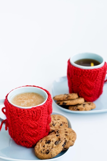 Taça azul com capa de malha vermelha e biscoitos com chocolate