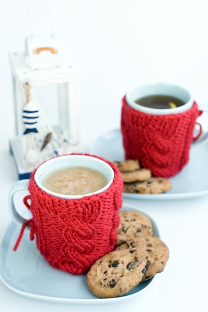 Taça azul com capa de malha vermelha e biscoitos com chocolate