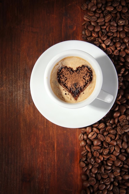 Taça de café com grãos de café em fundo de madeira