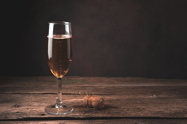 Taça de champanhe e uma rolha em uma mesa de madeira