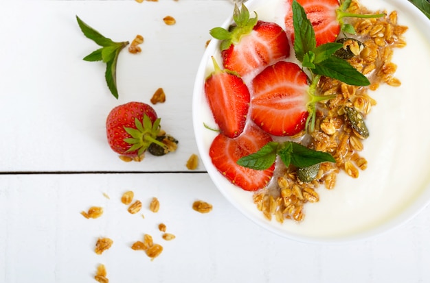 Taça de iogurte, granola e morangos