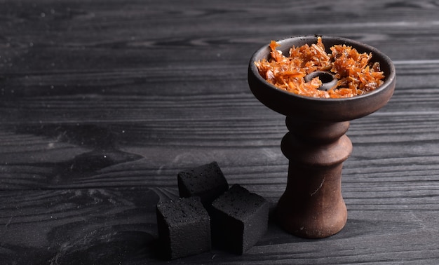 Taça de narguilé com tabaco e carvão para fumar em um espaço de fundo escuro para texto