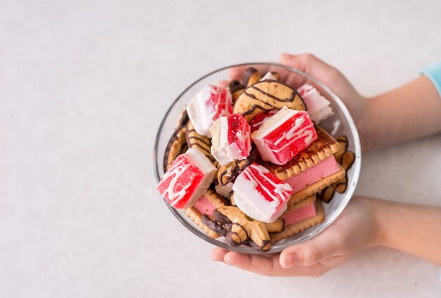 Taça de sobremesa doce em suas mãos. Biscoitos e geléia em um fundo branco