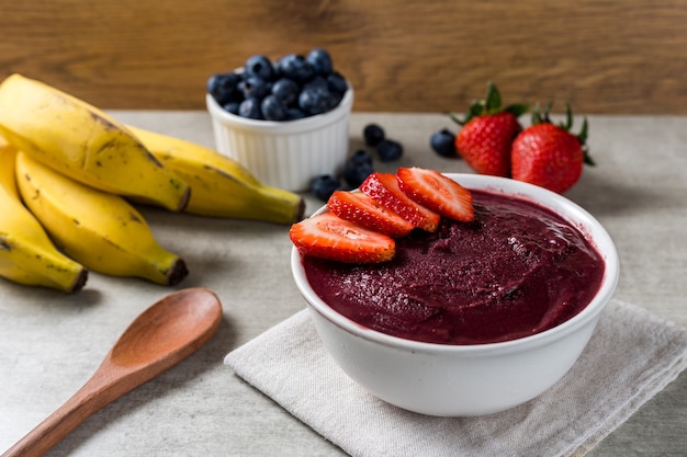 Taça de sorvete brasileiro de Açaí e congelados com morangos. com frutas em fundo de madeira. Vista frontal do menu de verão