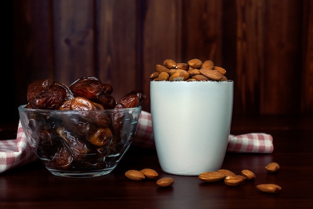 Taças com amêndoas e tâmaras na mesa de madeira