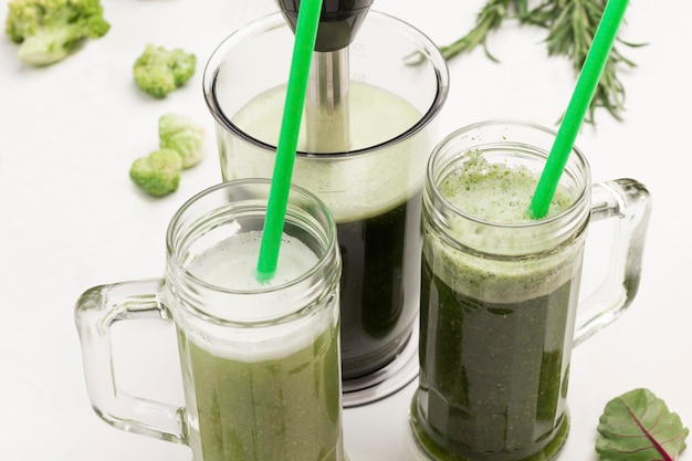 Taças com smoothies de vegetais verdes palhinhas verdes em taças close up fundo branco vista superior