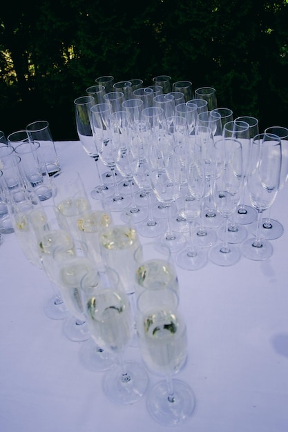 Taças de champanhe de casamento estão na mesa, em uma toalha de mesa branca no jardim