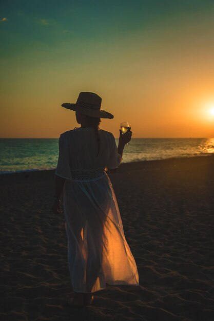 Taças de vinho ao pôr do sol na praia. Foco seletivo.