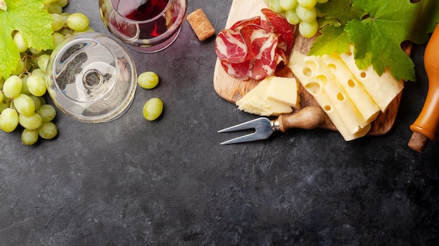 Taças de vinho branco e tinto uva e tábua de aperitivos