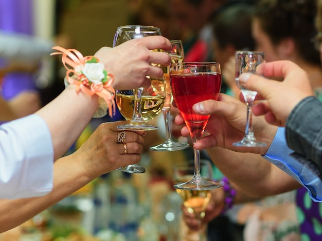 Taças de vinho nas mãos de amigos comemorando o feriado