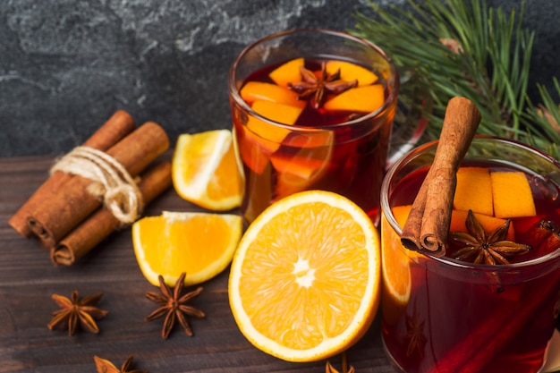 Taças de vinho quente com galhos de árvore do abeto na mesa de madeira