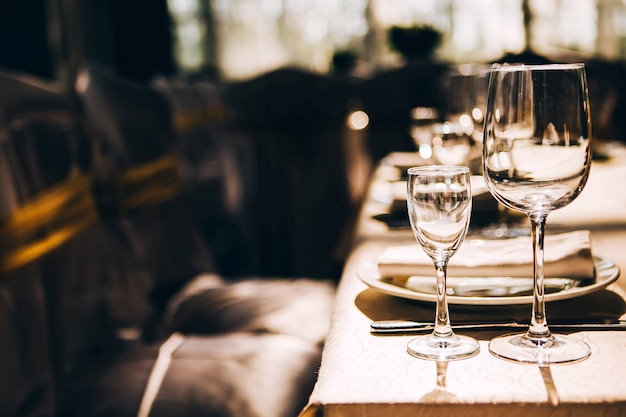 Taças de vinho vazias na luz do sol na mesa de banquete