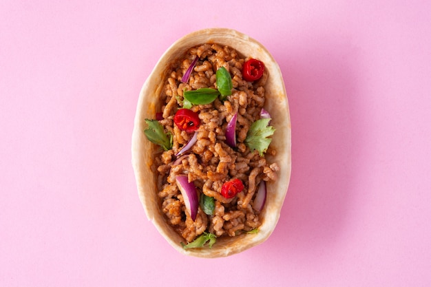 Taco de barquita mexicana con carne de res, chile, tomate, cebolla y especias aislado sobre fondo rosa