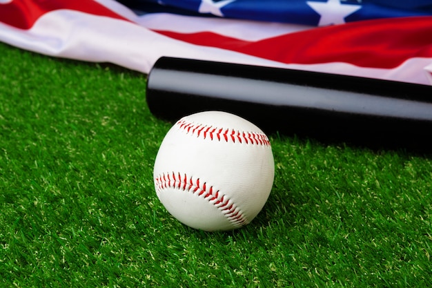 Foto taco de beisebol e bola com bandeira americana na grama