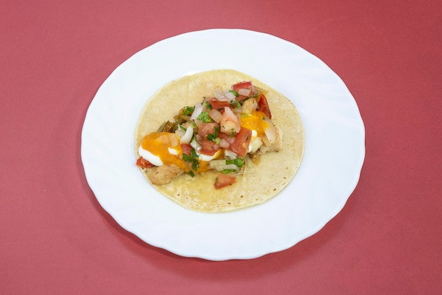 Taco mexicano com recheio de fajita com carne de frango cozido pico de gallo na chapa branca e fundo vermelho