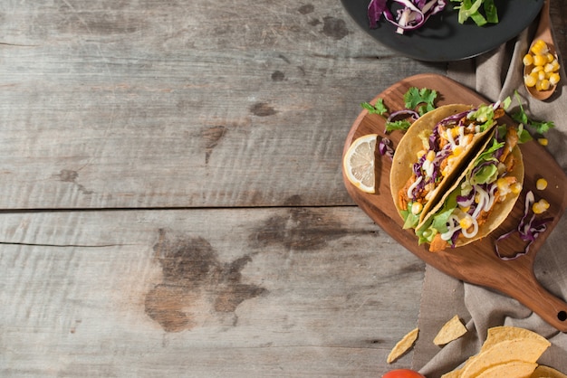 Taco mexicano tradicional con pollo y verduras en mesa de madera. Comida latinoamericana.