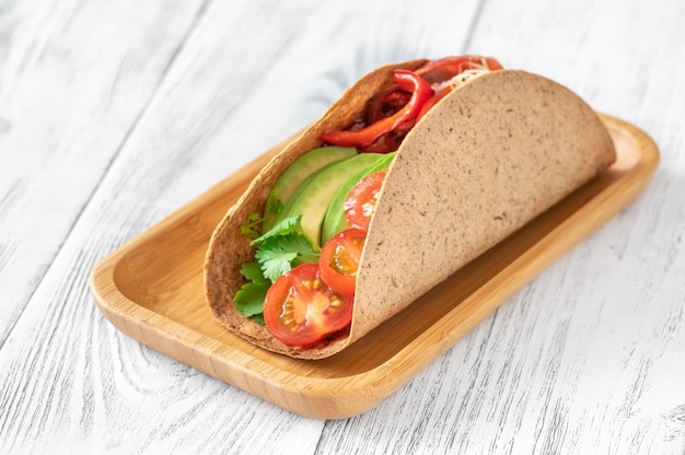 Taco mit Schinken und Gemüse auf der Servierplatte aus Holz