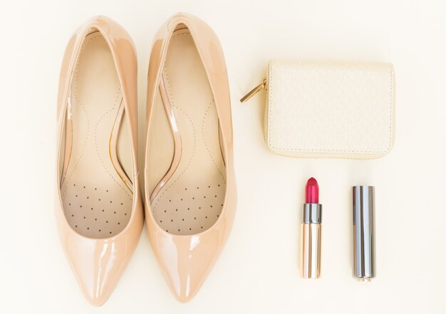 Tacones de color nude naturaleza muerta con billetera y lápiz labial rojo