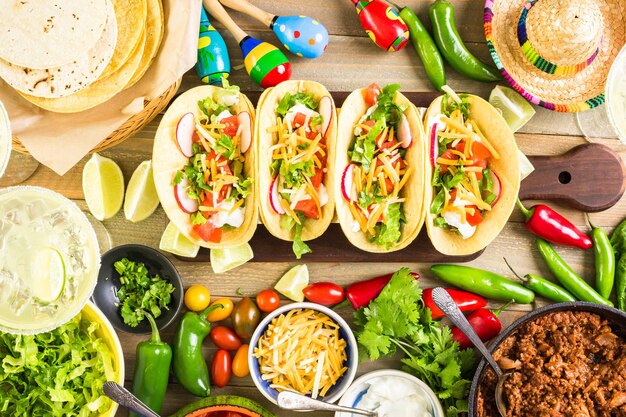 Tacos de carne molida con lechuga romana, tomates cortados en cubitos, rábanos y queso cheddar rallado.