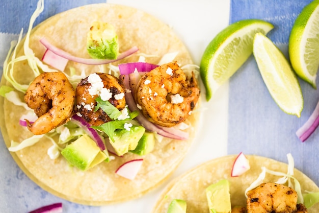 Tacos de camarão com chipotle fresco com queijo cotija em uma tortilhas de milho branco.