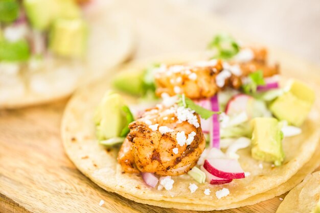 Tacos de camarão com chipotle fresco com queijo cotija em uma tortilhas de milho branco.