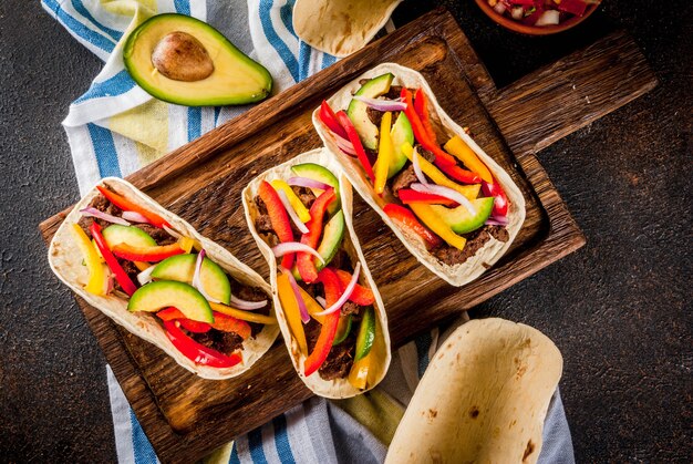 Tacos de carne de porco mexicana caseira com legumes e salsa, na vista superior da mesa enferrujada escura