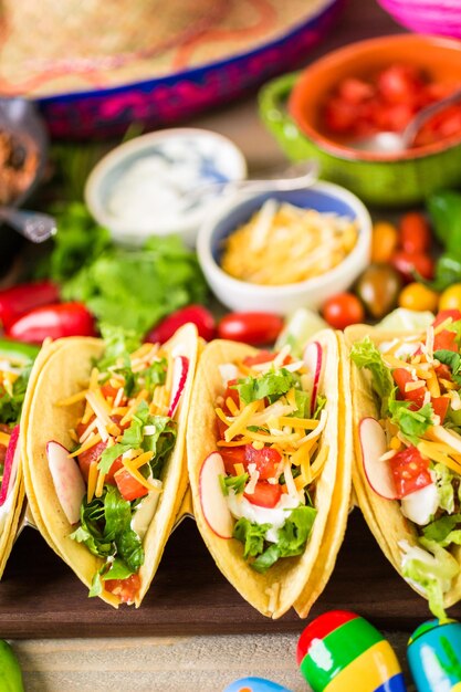 Tacos de carne moída com alface, tomate picado, rabanete e queijo cheddar ralado.