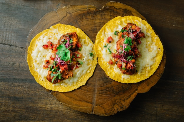 Tacos de frango grelhado com salada de tomate servido na tábua de madeira.