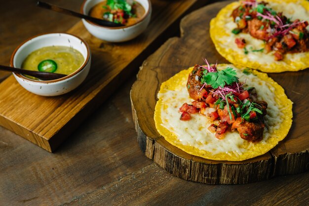 Tacos de frango grelhado com salada de tomate servido na tábua de madeira.