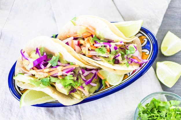 Tacos de peixe fresco com legumes e molho de guacamole em tortilhas de milho branco.