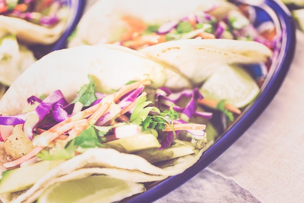 Tacos de peixe fresco com legumes e molho de guacamole em tortilhas de milho branco.