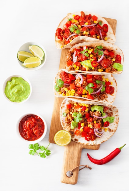 Tacos mexicanos de carne de res y cerdo con salsa, guacamole y vegetales