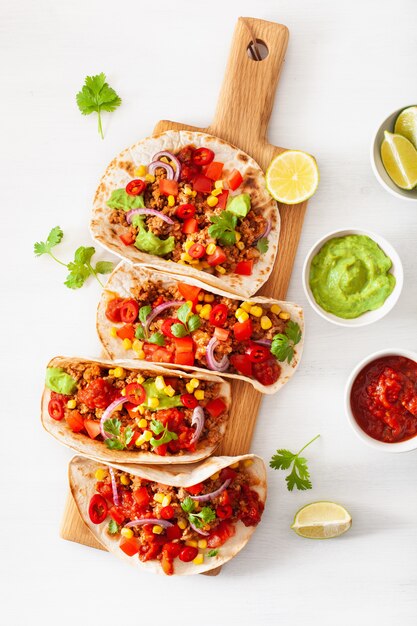 Tacos mexicanos de carne de res y cerdo con salsa, guacamole y vegetales