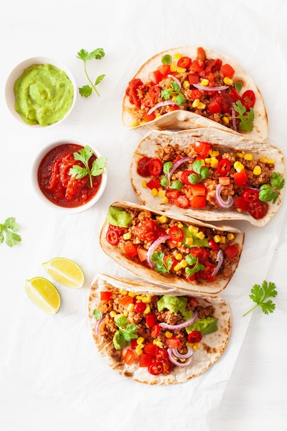 Tacos mexicanos de carne de res y cerdo con salsa, guacamole y vegetales