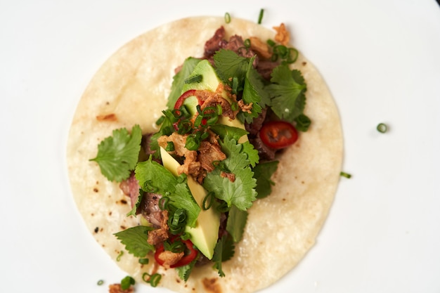 Tacos mexicanos con carne de res, tomate, aguacate, chile y cebolla.