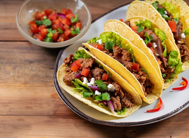 Tacos mexicanos con carne de res en tomate y ensalada en una mesa de madera