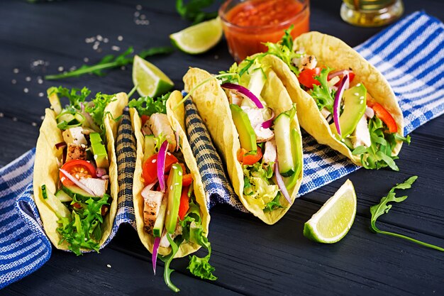 Tacos mexicanos com carne de frango, abacate, tomate, pepino e cebola vermelha.