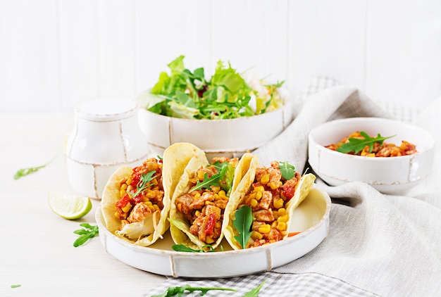 Tacos mexicanos com carne de frango, molho de milho e tomate.