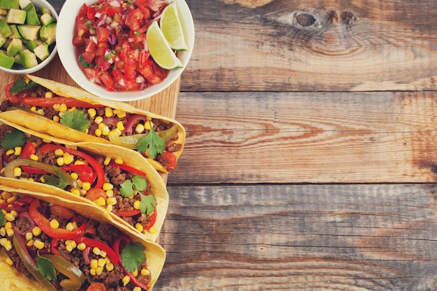 Tacos mexicanos com carne picada, legumes e salsa.