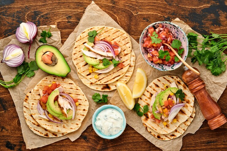 Tacos mexicanos com frango grelhado, abacate, miolo de milho, tomate, cebola, coentro e salsa velha mesa de madeira. Comida de rua tradicional mexicana e latino-americana. Vista do topo.
