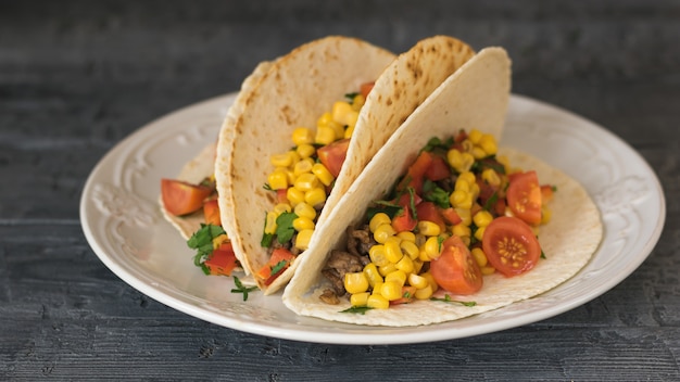 Foto tacos mexicanos recién preparados en un plato sobre una mesa rústica