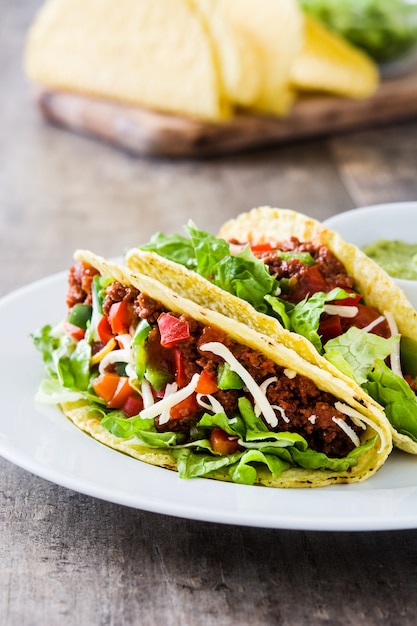 Tacos mexicanos tradicionais com carne e legumes na madeira