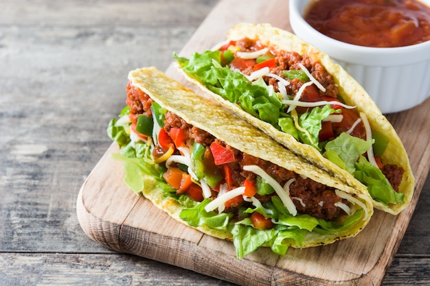 Tacos mexicanos tradicionais com carne e legumes na madeira