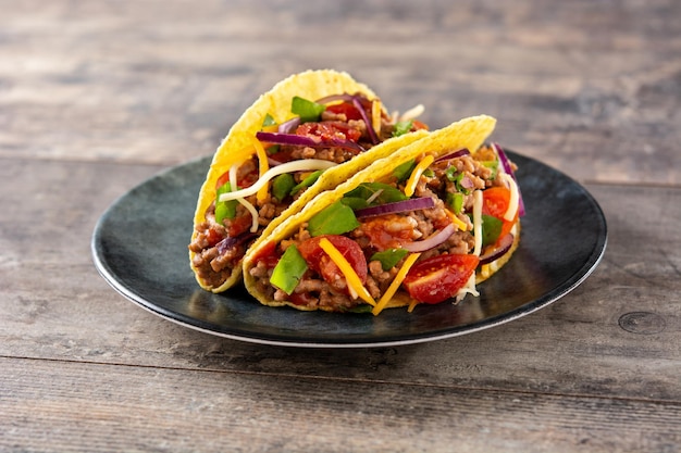 Tacos mexicanos tradicionales con carne y verduras en la mesa de madera