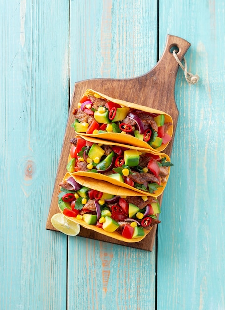 Tacos mit Schweinefleisch, Avocado, Tomaten, Mais und Zwiebeln. Mexikanische Nahrung.