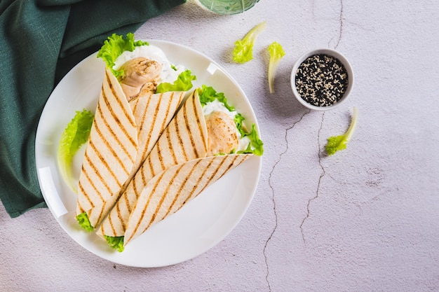 Tacos a la parrilla dietéticos con lechuga de filete de pollo en un plato en la vista de la mesa